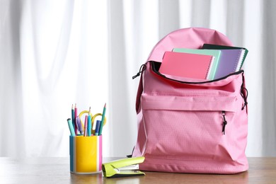 Photo of Backpack with different school stationery on wooden table