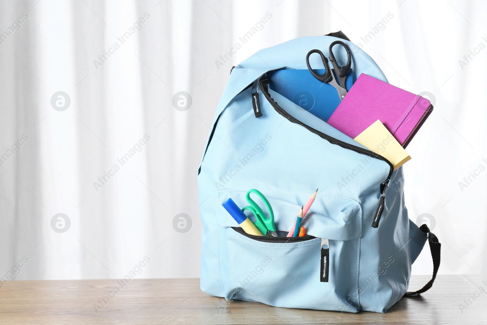 Photo of Backpack with different school stationery on wooden table