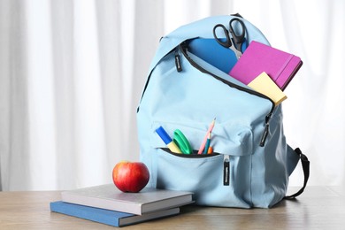 Photo of Backpack with different school stationery and apple y on wooden table