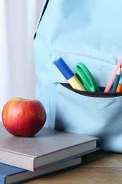 Photo of Backpack with different school stationery and apple y on wooden table