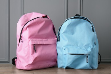 Bright backpacks on wooden table near grey wall