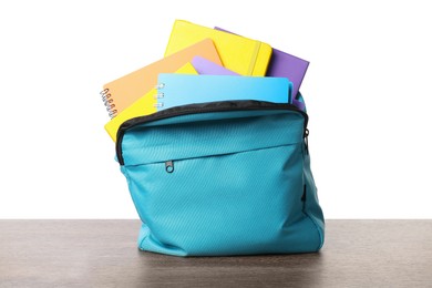 Photo of Backpack with different school stationery on wooden table against white background