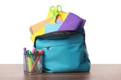 Photo of Backpack with different school stationery on wooden table against white background