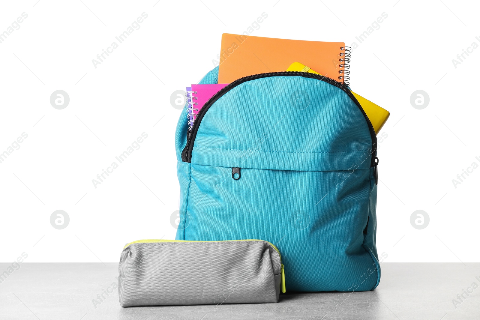 Photo of Backpack with different school stationery on light grey table against white background