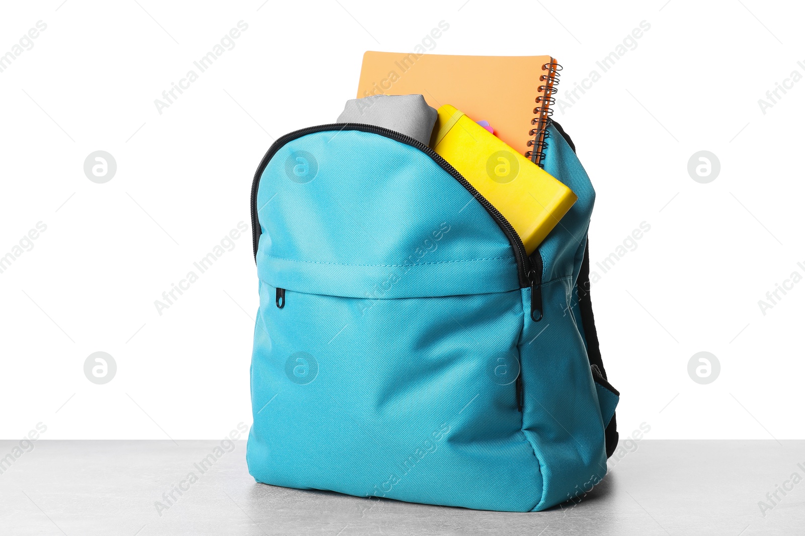 Photo of Backpack with different school stationery on light grey table against white background