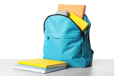 Photo of Backpack with different school stationery on light grey table against white background