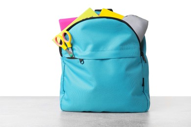 Photo of Backpack with different school stationery on light grey table against white background