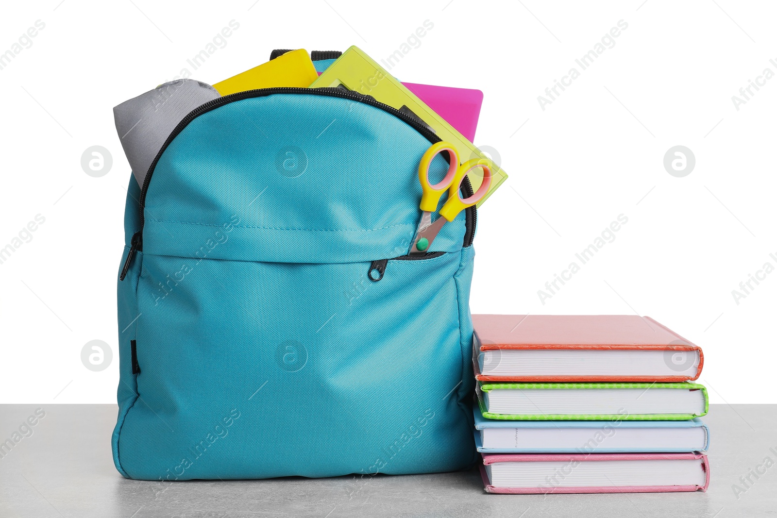 Photo of Backpack with different school stationery on light grey table against white background