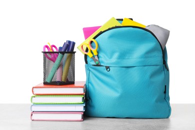 Photo of Backpack with different school stationery on light grey table against white background