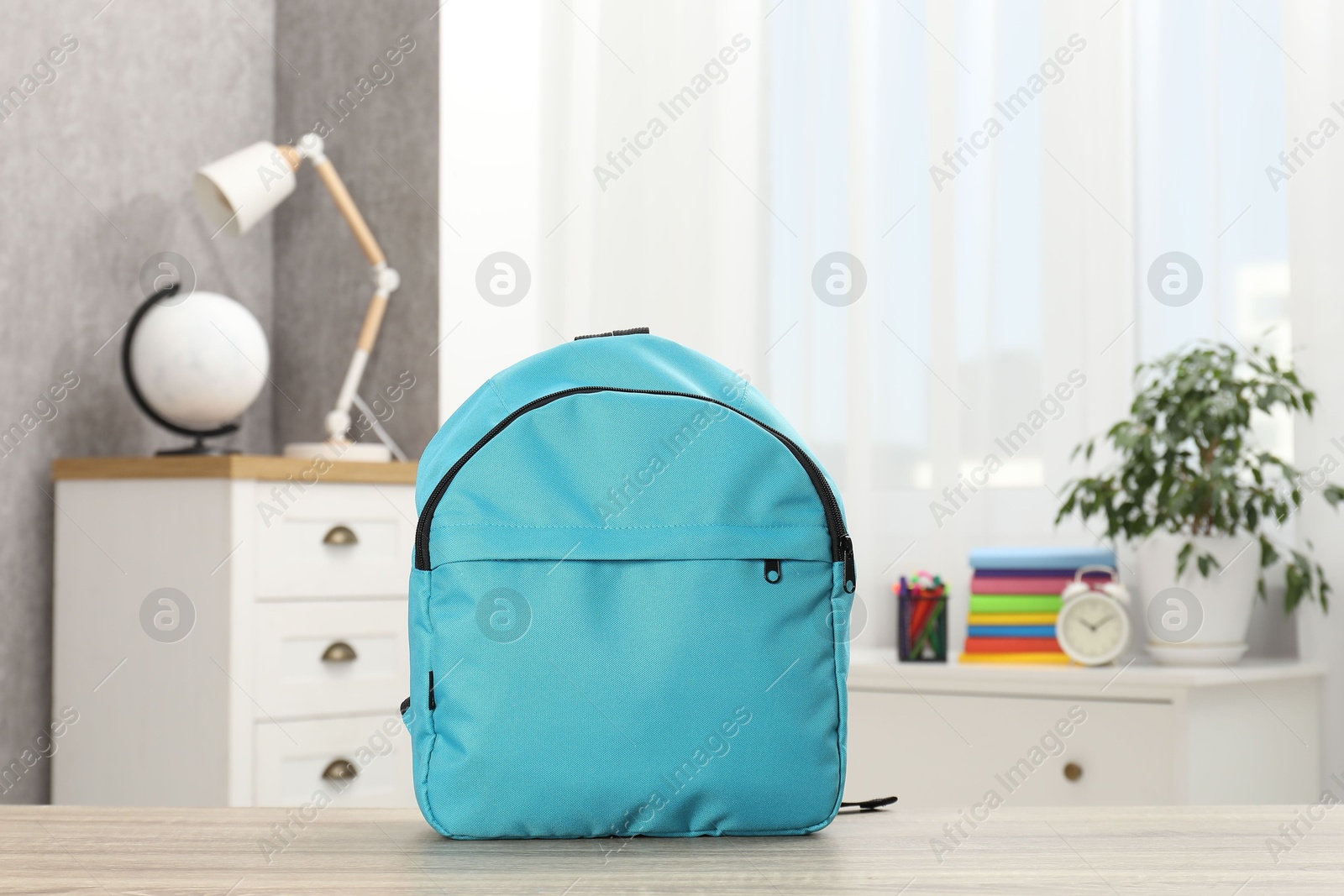 Photo of Light blue backpack on desk in room