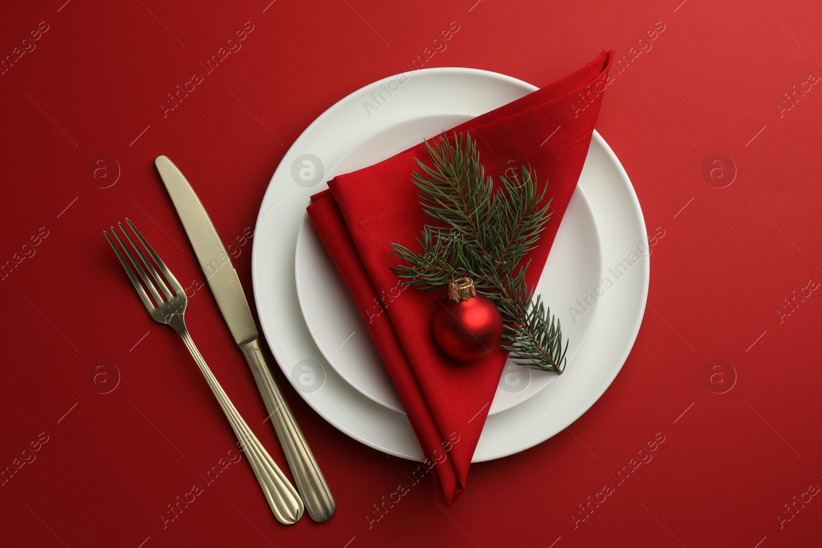 Photo of Beautiful Christmas setting with plates, elegant cutlery and festive decor on red table, flat lay