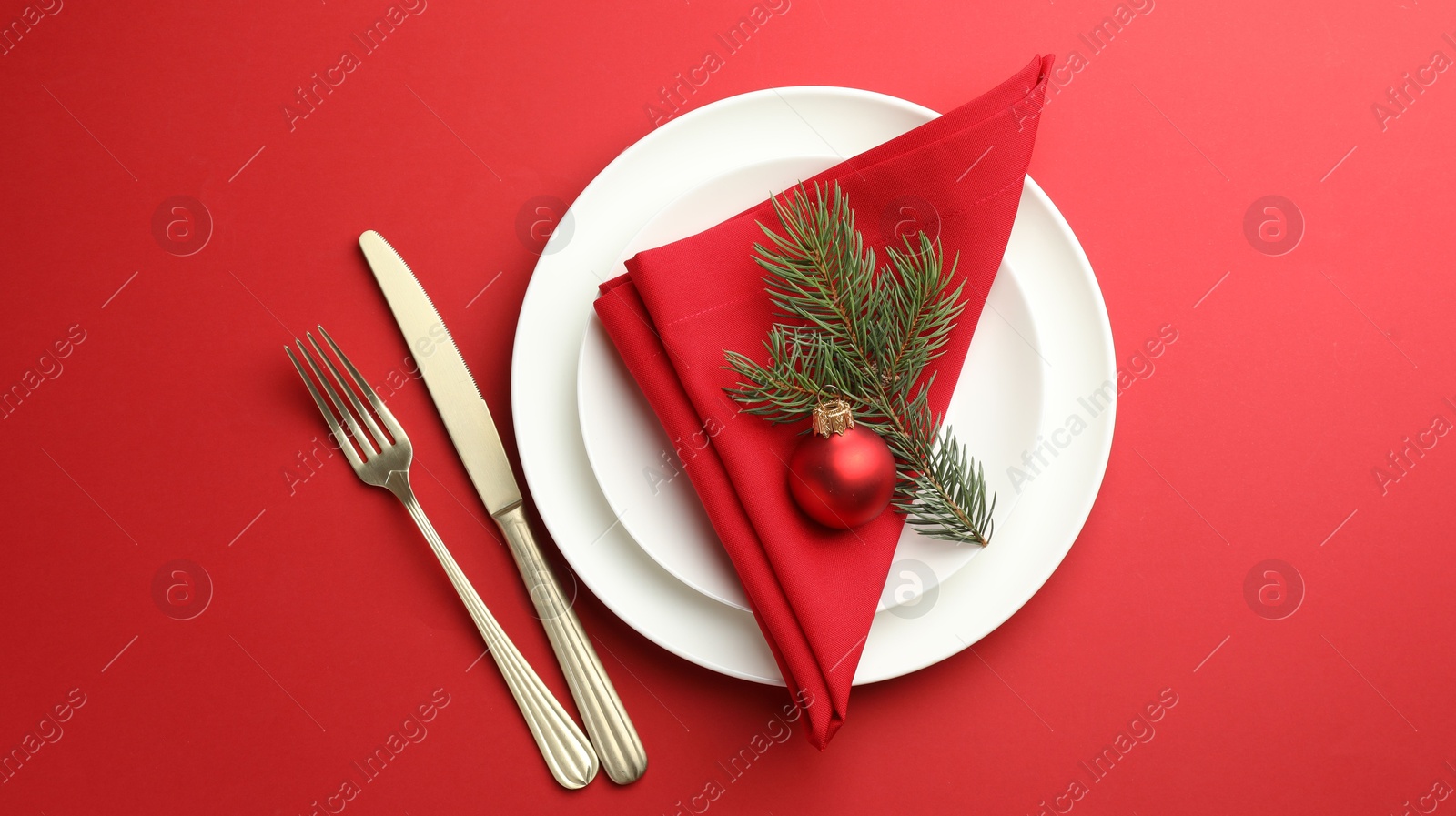 Photo of Beautiful Christmas setting with plates, elegant cutlery and festive decor on red table, flat lay