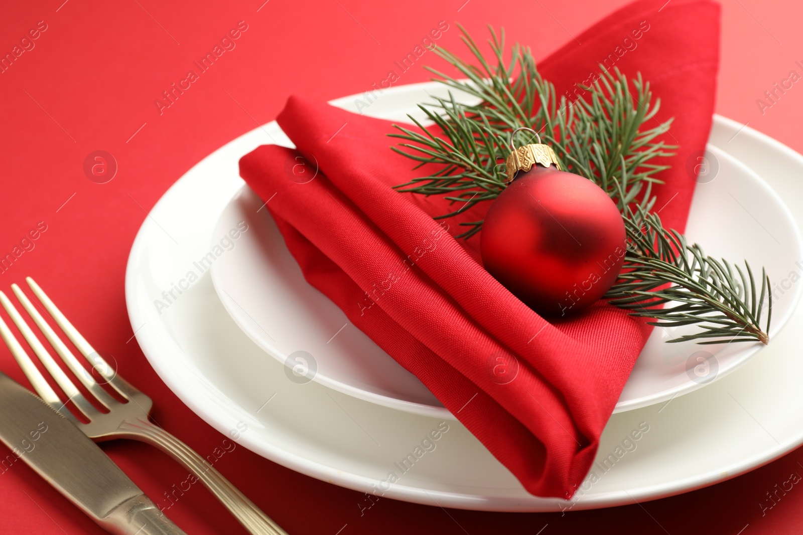 Photo of Beautiful Christmas setting with plates, elegant cutlery and festive decor on red table