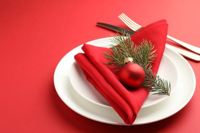 Photo of Beautiful Christmas setting with plates, elegant cutlery and festive decor on red table