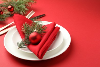 Photo of Beautiful Christmas setting with plates, elegant cutlery and festive decor on red table