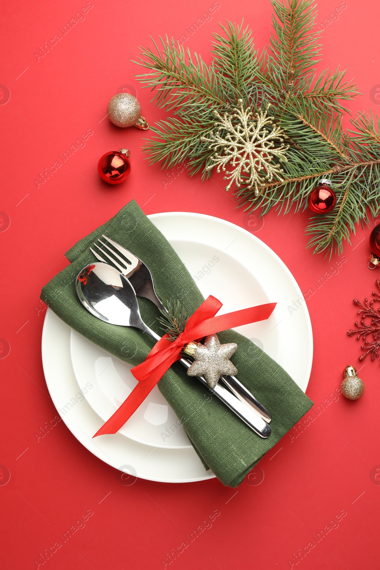 Photo of Beautiful Christmas setting with plates, elegant cutlery and festive decor on red table, flat lay