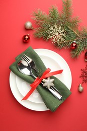 Photo of Beautiful Christmas setting with plates, elegant cutlery and festive decor on red table, flat lay