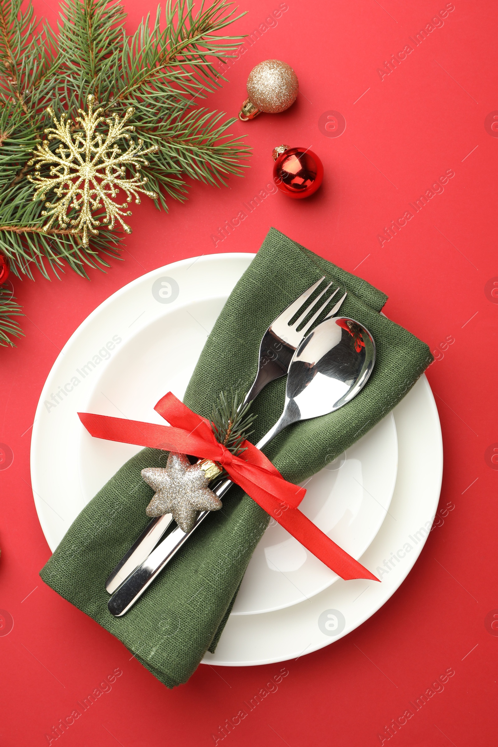 Photo of Beautiful Christmas setting with plates, elegant cutlery and festive decor on red table, flat lay