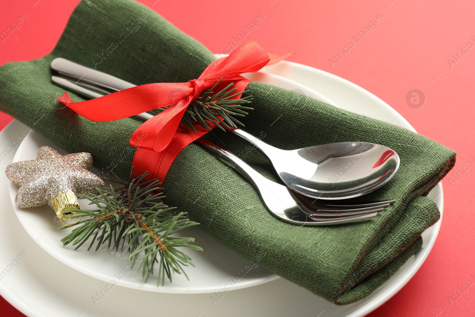 Photo of Beautiful Christmas setting with plates, elegant cutlery and festive decor on red table, closeup