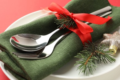 Photo of Beautiful Christmas setting with plates, elegant cutlery and festive decor on red table, closeup