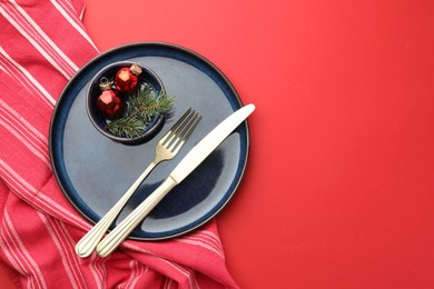 Photo of Beautiful Christmas setting with plate, elegant cutlery and festive decor on red table, flat lay. Space for text