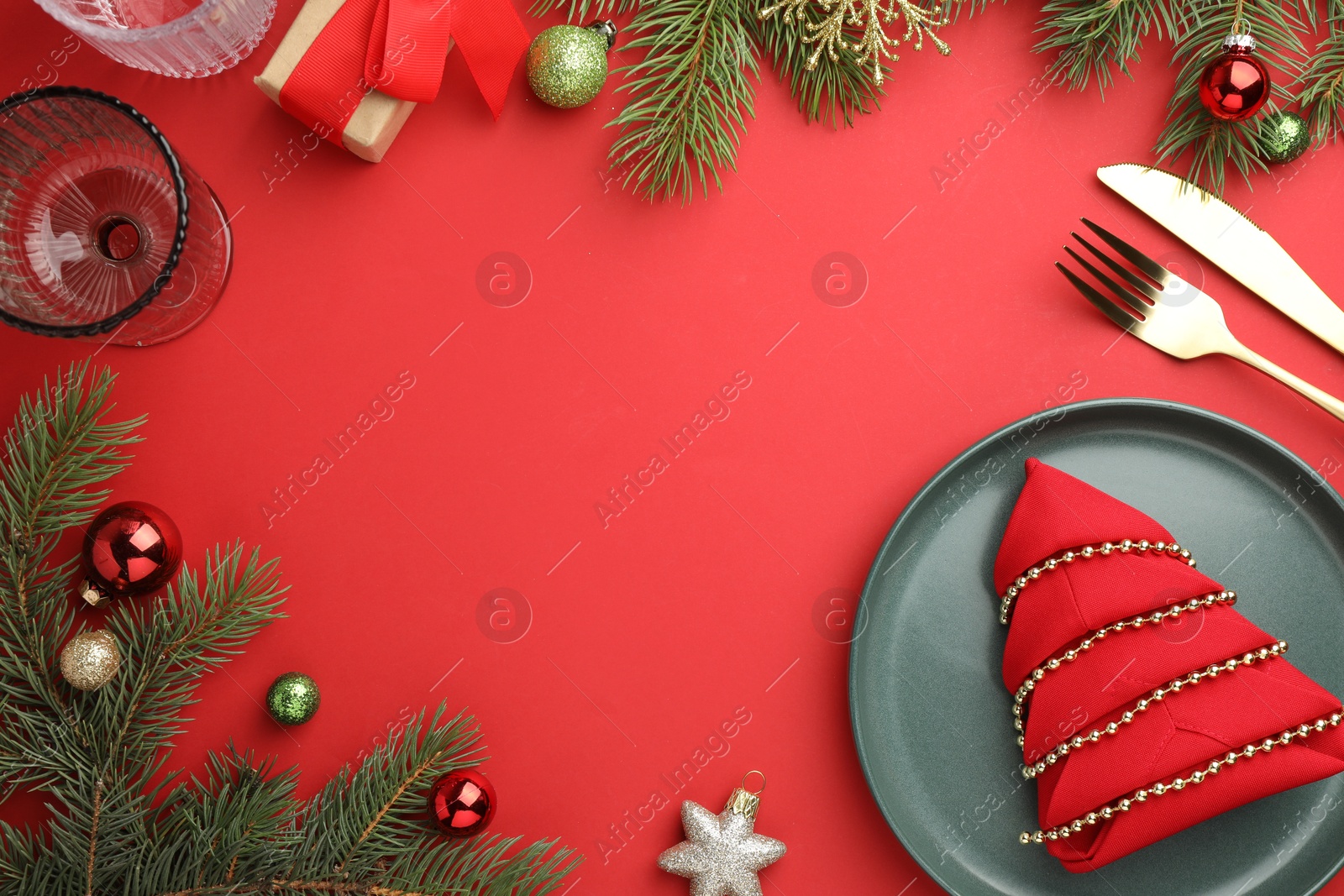 Photo of Beautiful Christmas setting with plate, elegant cutlery and festive decor on red table, flat lay. Space for text