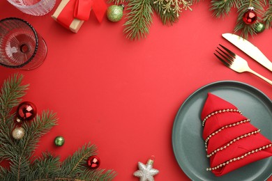 Photo of Beautiful Christmas setting with plate, elegant cutlery and festive decor on red table, flat lay. Space for text