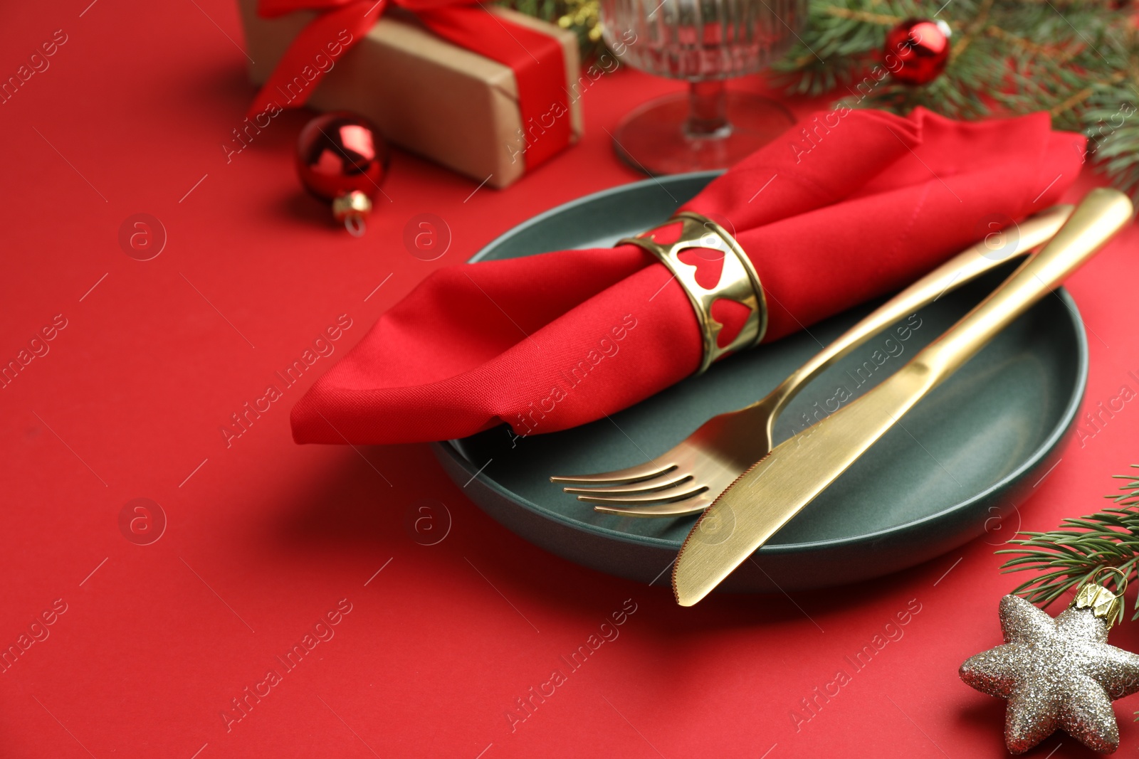 Photo of Beautiful Christmas setting with plate, elegant cutlery and festive decor on red table