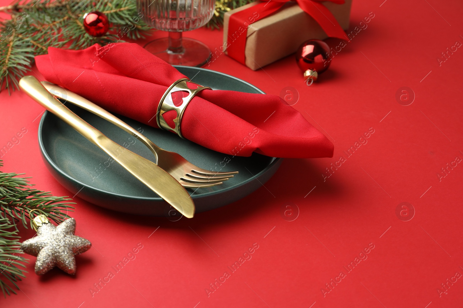 Photo of Beautiful Christmas setting with plate, elegant cutlery and festive decor on red table