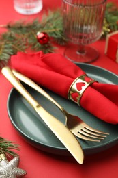 Photo of Beautiful Christmas setting with plate, elegant cutlery and festive decor on red table