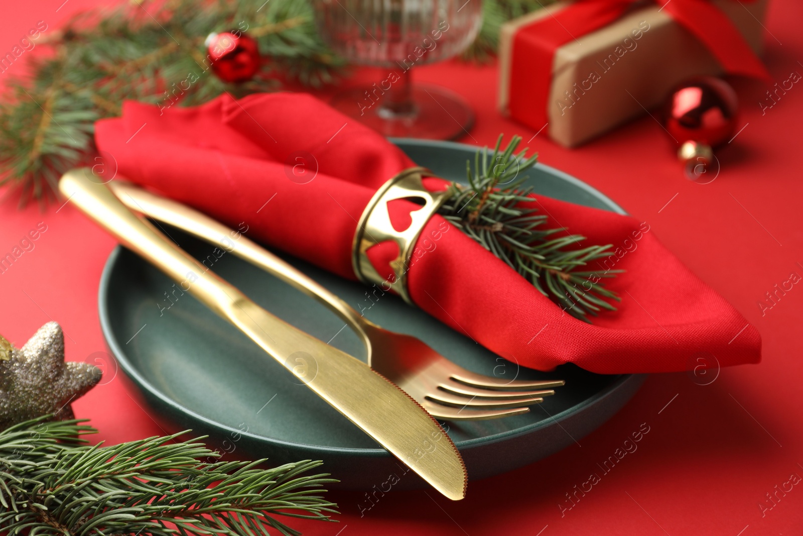 Photo of Beautiful Christmas setting with plate, elegant cutlery and festive decor on red table, closeup