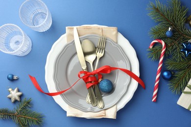 Photo of Beautiful Christmas setting with plates, elegant cutlery and festive decor on blue table, flat lay