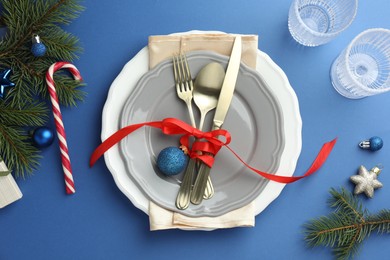 Photo of Beautiful Christmas setting with plates, elegant cutlery and festive decor on blue table, flat lay