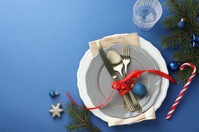 Photo of Beautiful Christmas setting with plates, elegant cutlery and festive decor on blue table, flat lay. Space for text