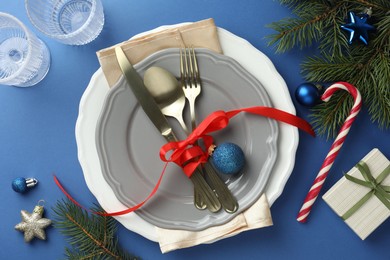 Photo of Beautiful Christmas setting with plates, elegant cutlery and festive decor on blue table, flat lay