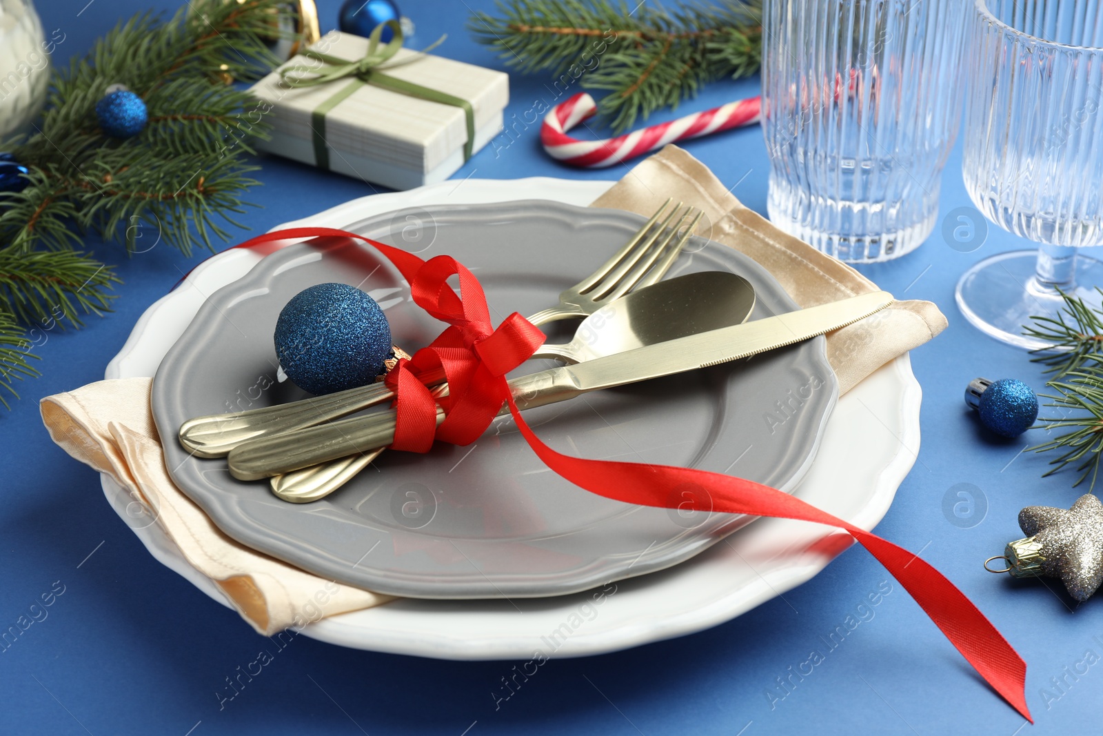 Photo of Beautiful Christmas setting with plates, elegant cutlery and festive decor on blue table, closeup