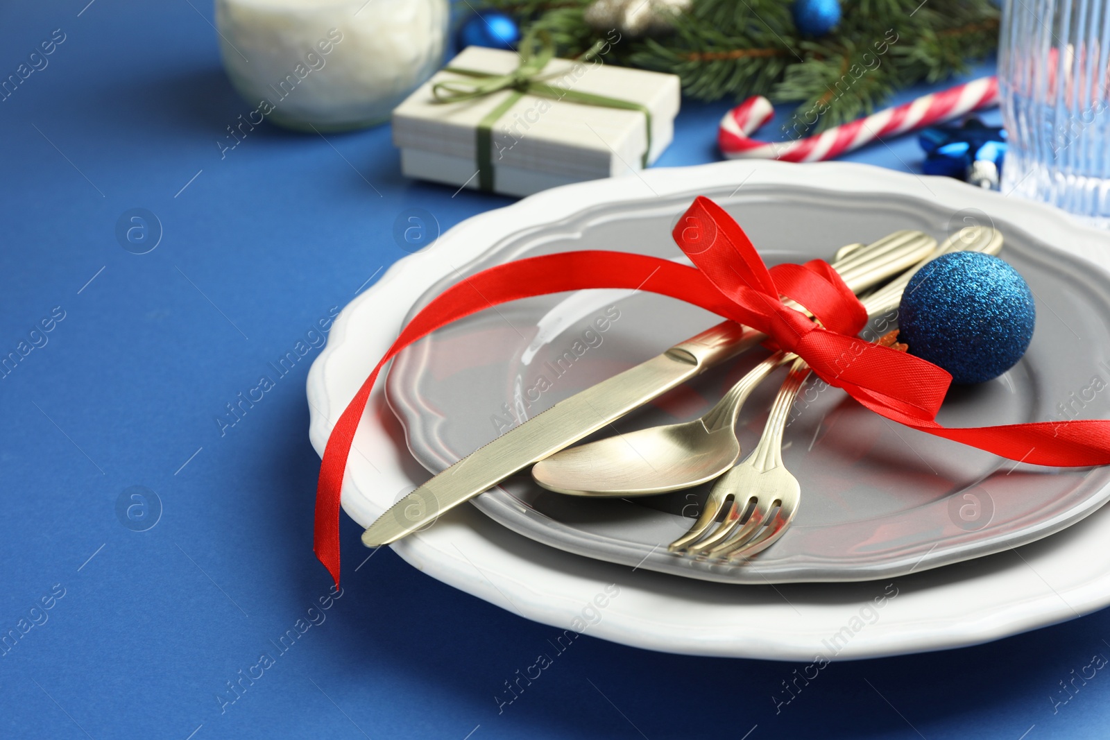 Photo of Beautiful Christmas setting with plates, elegant cutlery and festive decor on blue table