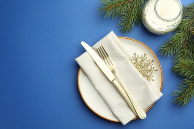 Photo of Beautiful Christmas setting with plate, elegant cutlery and festive decor on blue table, flat lay. Space for text