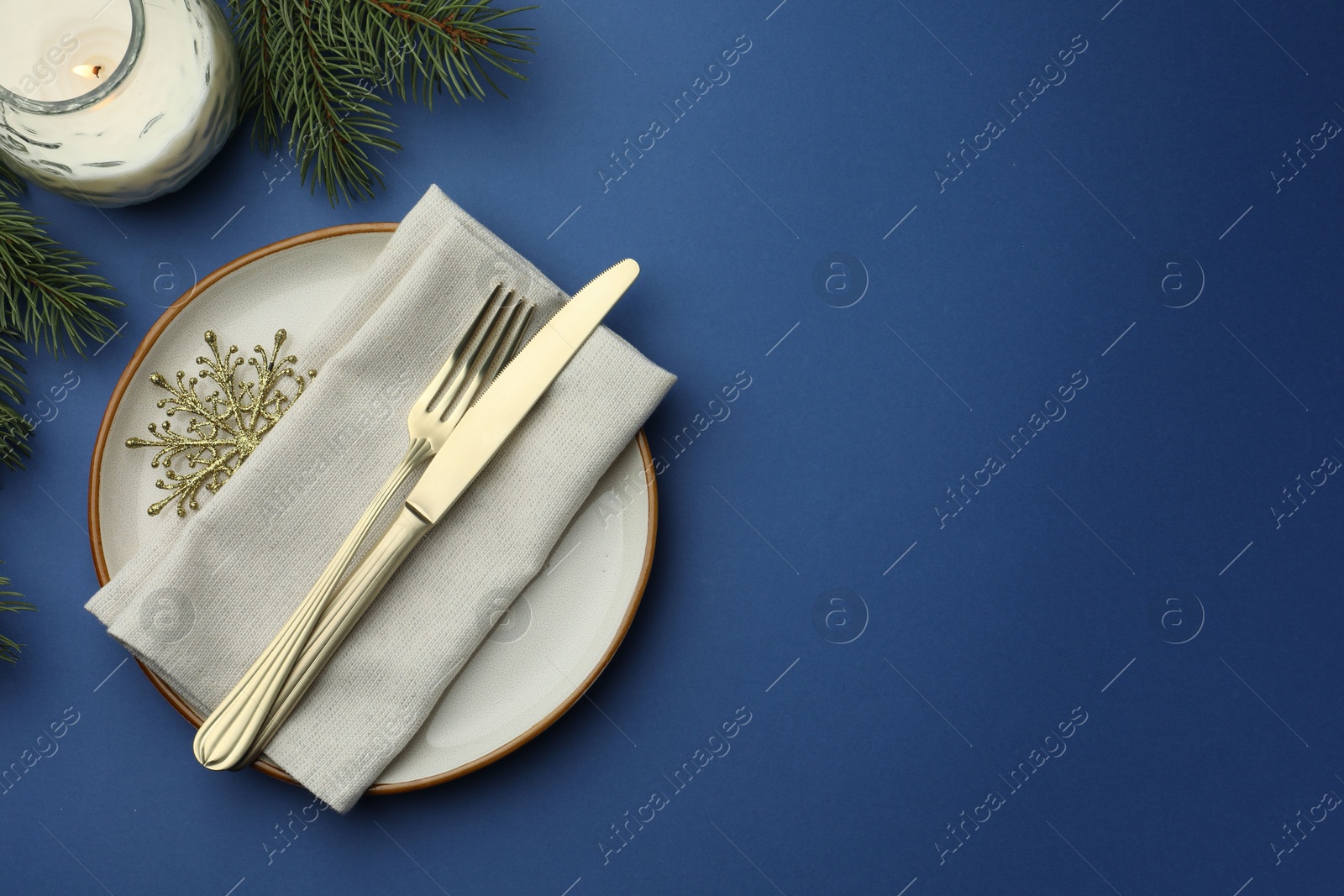 Photo of Beautiful Christmas setting with plate, elegant cutlery and festive decor on blue table, flat lay. Space for text