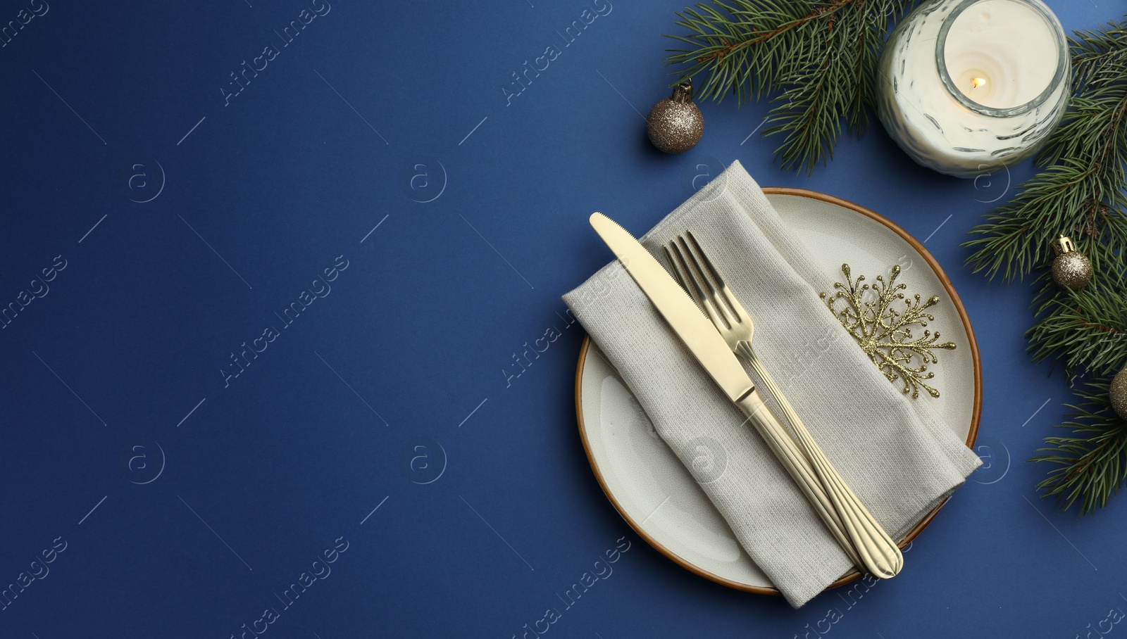 Photo of Beautiful Christmas setting with plate, elegant cutlery and festive decor on blue table, flat lay. Space for text