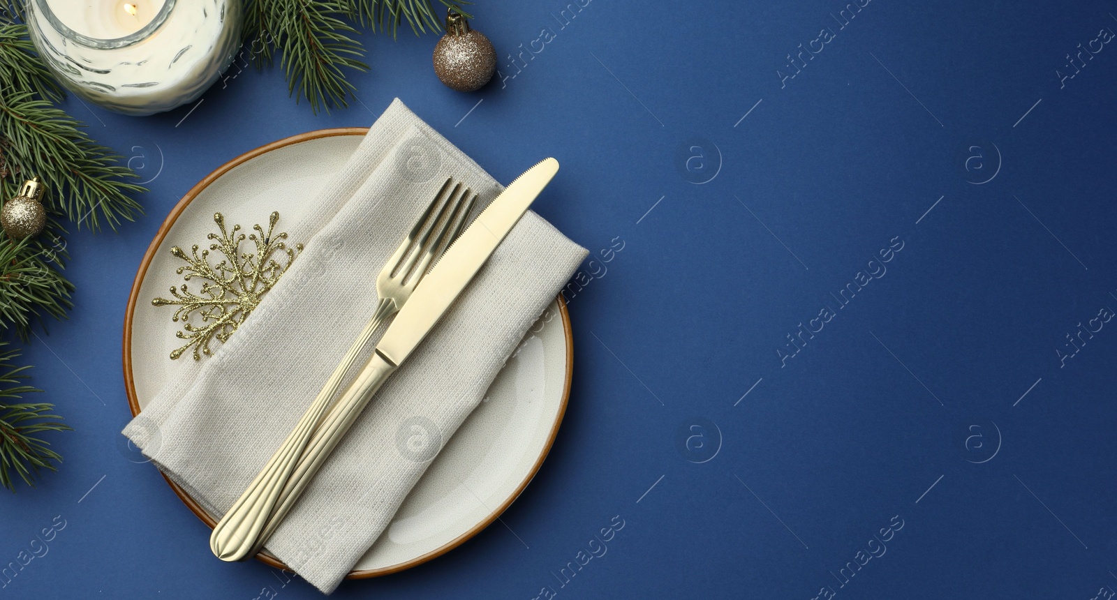 Photo of Beautiful Christmas setting with plate, elegant cutlery and festive decor on blue table, flat lay. Space for text