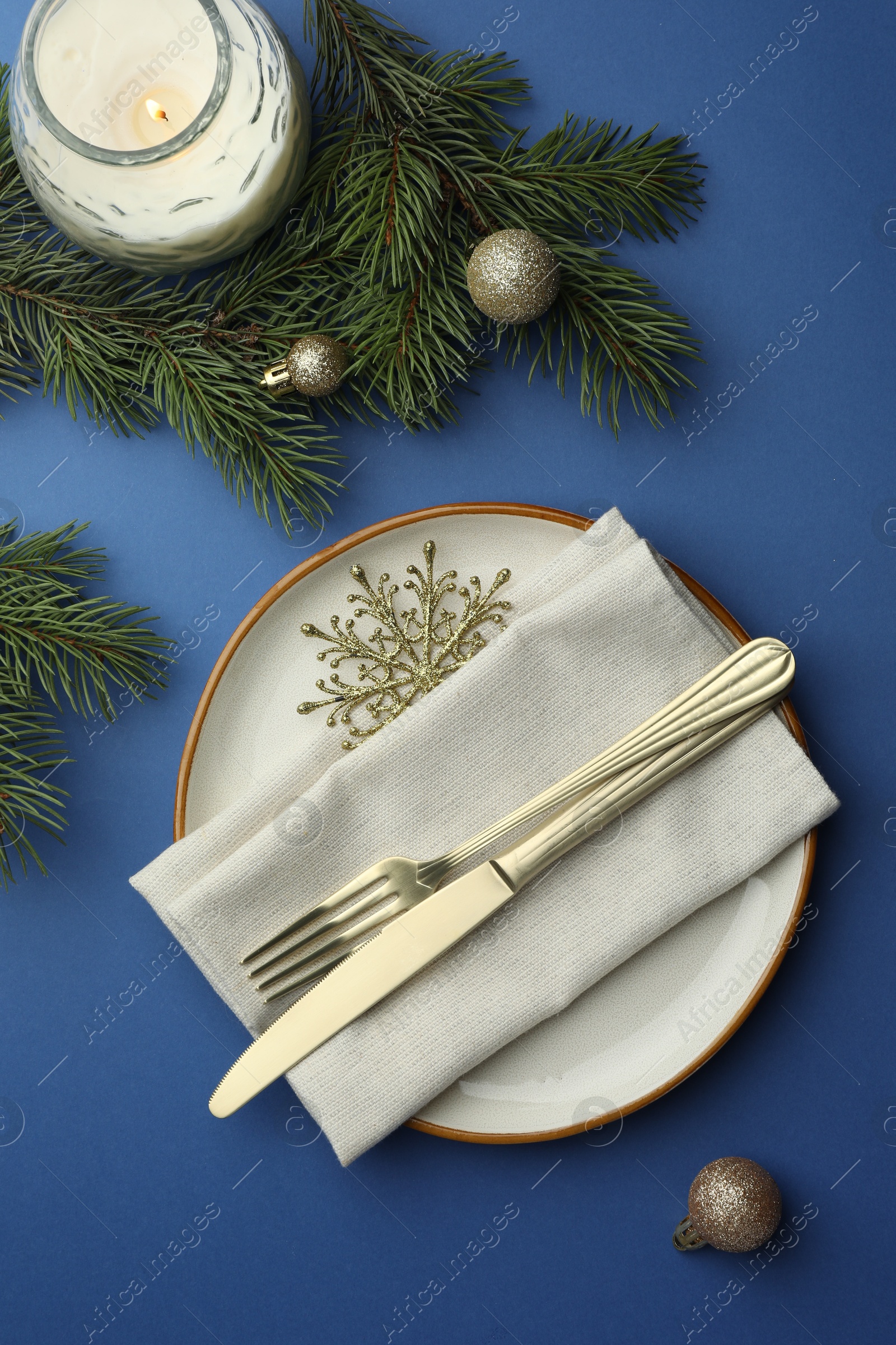 Photo of Beautiful Christmas setting with plate, elegant cutlery and festive decor on blue table, flat lay