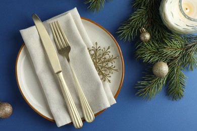 Photo of Beautiful Christmas setting with plate, elegant cutlery and festive decor on blue table, flat lay