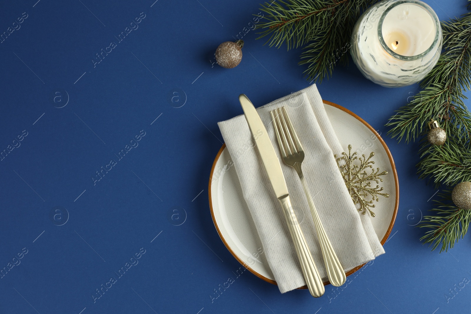 Photo of Beautiful Christmas setting with plate, elegant cutlery and festive decor on blue table, flat lay. Space for text