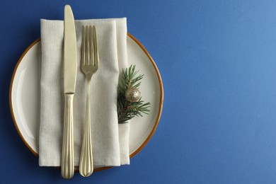 Photo of Beautiful Christmas setting with plate, elegant cutlery and festive decor on blue table, top view. Space for text