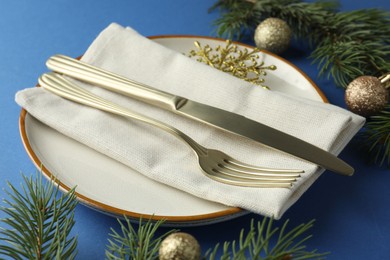 Photo of Beautiful Christmas setting with plate, elegant cutlery and festive decor on blue table, closeup