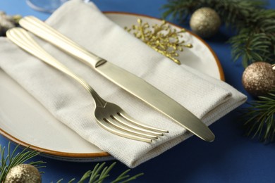 Photo of Beautiful Christmas setting with plate, elegant cutlery and festive decor on blue table, closeup