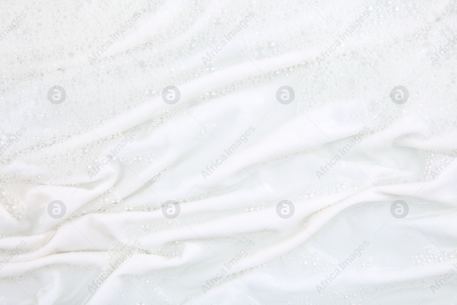 Photo of Washing laundry in water with foam, top view