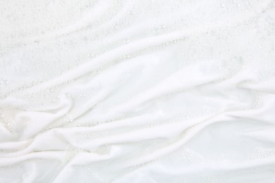 Photo of Washing laundry in water with foam, top view