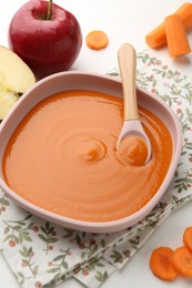 Photo of Delicious baby food in bowl and ingredients on white table